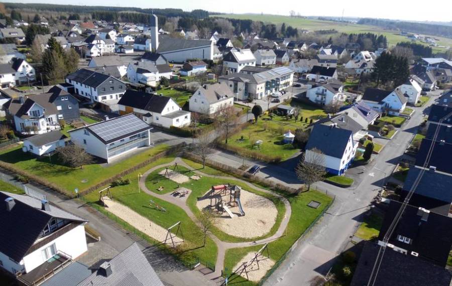 Luftbildaufnahme aus süd-westlicher Richtung von Spielplatz, Bürgerhaus, Kirche und Umgebung